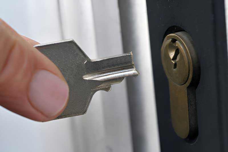 Person holding a key near a lock, illustrating key insertion for broken key extraction services offered by Tiger Locksmith.