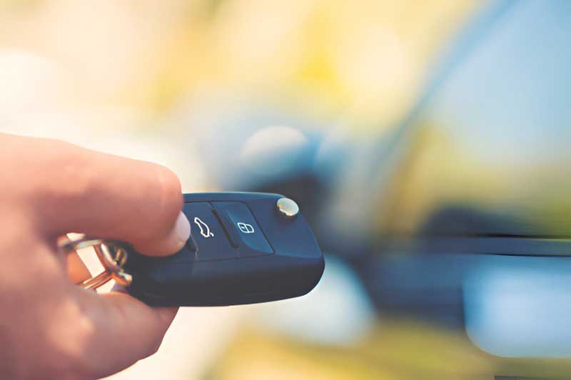 Car key remote held in hand, showcasing features related to automotive locksmith services, including key and remote replacement options.