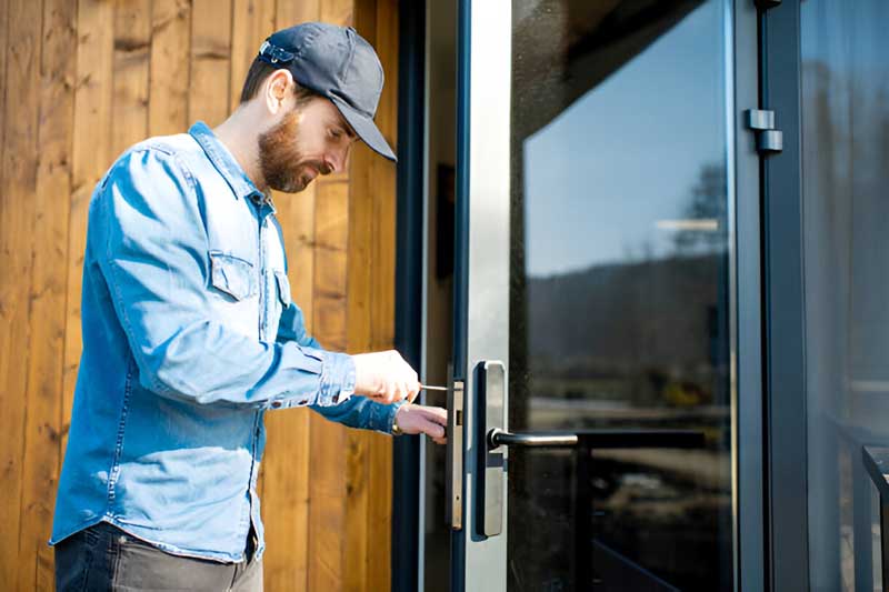 Man performing lock change and installation service on a modern door, showcasing residential locksmith expertise in Wilmington.