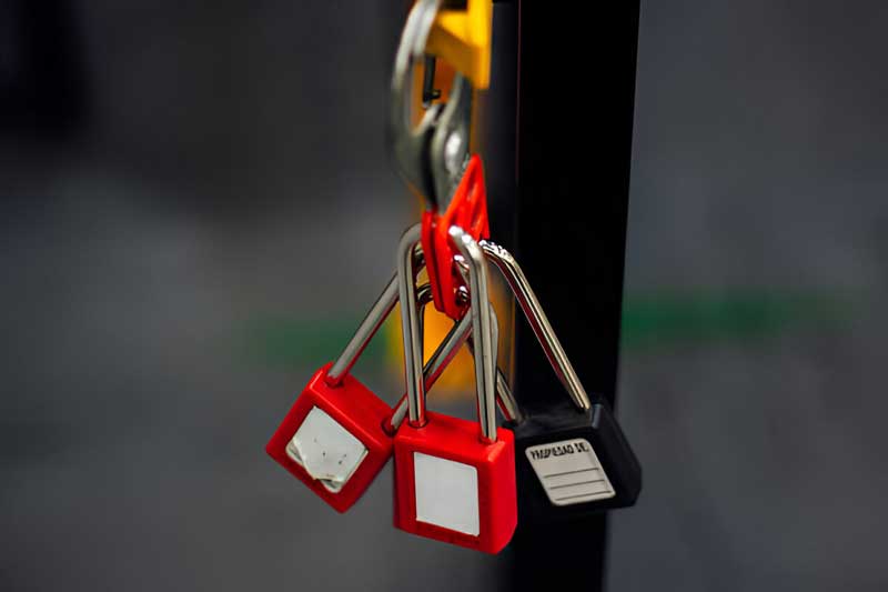 Red and black padlocks hanging from a metal hook, symbolizing security and lockout services related to Tiger Locksmith's offerings.