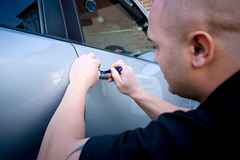 Automotive locksmith working on a car door lock, demonstrating professional key and remote replacement services by Tiger Locksmith.
