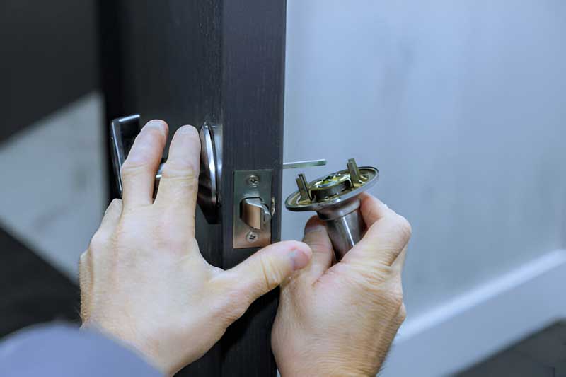Hands installing a door knob on a wooden door, demonstrating emergency locksmith services by Tiger Locksmith.